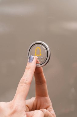 Asansör düğmesine basan bir kadının yakın plan portresi.