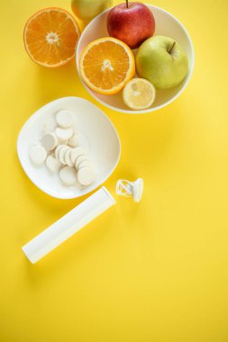 Beyaz tabaklar üzerinde meyveler ve beyaz haplar, sentetik vitaminlere karşı meyve konsepti