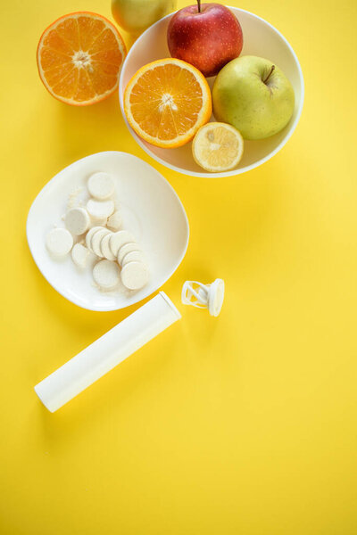 Вид сверху на фрукты и белые таблетки на белых пластинках, концепция фруктов против синтетических витаминов
