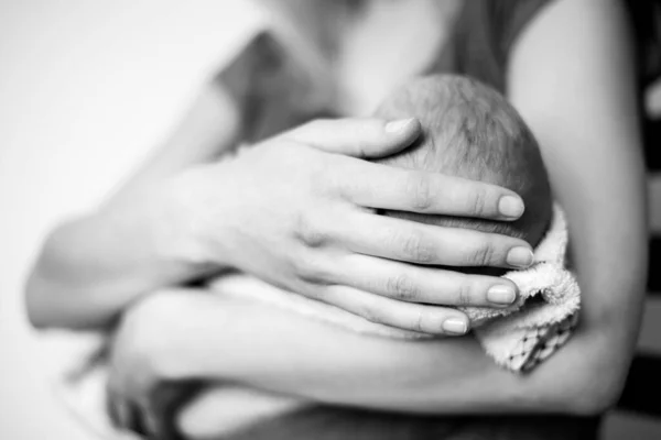 Black and white Close up view of gentle female hand holding the fingers of a newborn