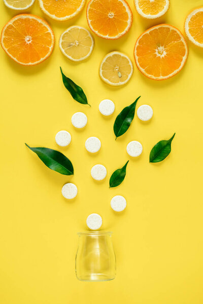 Вид сверху на скользкие цитрусовые и таблетки душицы, вылетающие из банки, концепция выбора фруктов против синтетических витаминов
