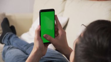 Yeşil ekran yeşil ekranda elinde akıllı telefon tutan bir adam. Elinde krom kaplı cep telefonu tutan bir adam.
