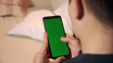 Yeşil ekran yeşil ekranda elinde akıllı telefon tutan bir adam. Elinde krom kaplı cep telefonu tutan bir adam.