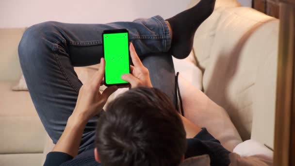 Mann hält Smartphone in den Händen eines grünen Bildschirms, Hand des Mannes hält Handy mit Chroma — Stockvideo
