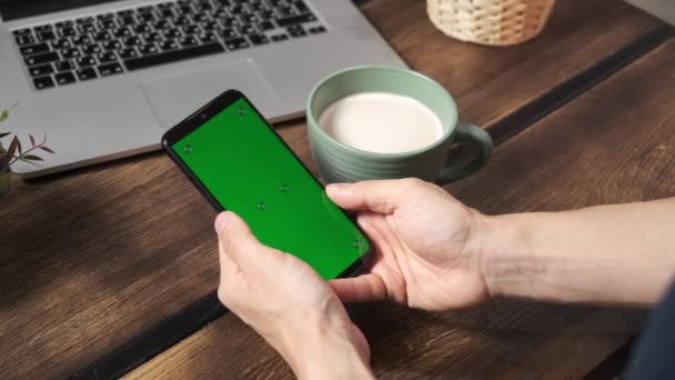 Yeşil ekran yeşil ekranda elinde akıllı telefon tutan bir adam. Elinde krom kaplı cep telefonu tutan bir adam. — Stok video