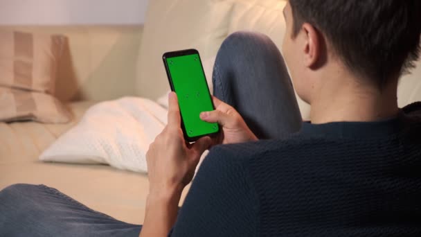 Yeşil ekran yeşil ekranda elinde akıllı telefon tutan bir adam. Elinde krom kaplı cep telefonu tutan bir adam. — Stok video