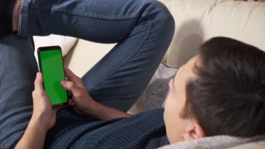 Yeşil ekran yeşil ekranda elinde akıllı telefon tutan bir adam. Elinde krom kaplı cep telefonu tutan bir adam.