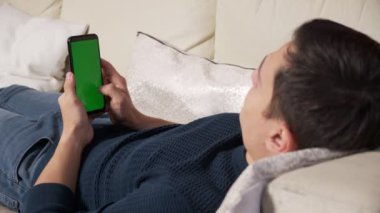 Yeşil ekran yeşil ekranda elinde akıllı telefon tutan bir adam. Elinde krom kaplı cep telefonu tutan bir adam.