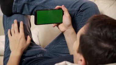 Yeşil ekran yeşil ekranda elinde akıllı telefon tutan bir adam. Elinde krom kaplı cep telefonu tutan bir adam.