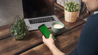 Yeşil ekran yeşil ekranda elinde akıllı telefon tutan bir adam. Elinde krom kaplı cep telefonu tutan bir adam.