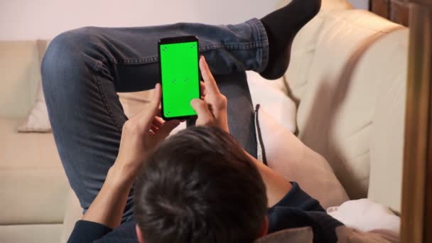 Man met een smartphone in de handen van een groen scherm, hand van een man met een mobiele telefoon met chroma — Stockvideo
