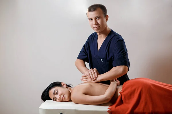 Una joven recibe un procedimiento de masaje. Masajista hace masaje de espalda. —  Fotos de Stock