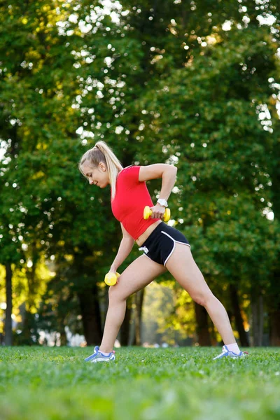 A young woman goes in for sports outdoors. girl with blond hair is training in the park on the nature Royalty Free Stock Photos