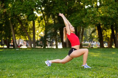 Hamle yapan bir kız. Şehir parkında hamleler yapan zayıf bir genç kadın. Açık hava sporları. Sağlıklı yaşam tarzı kavramı. Sabah egzersizleri.