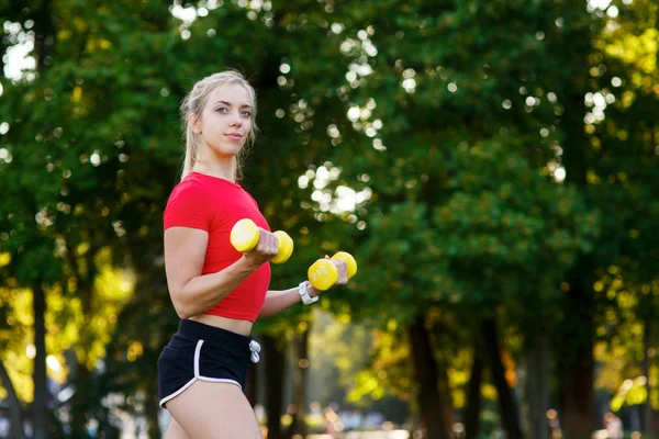 Una joven entra para practicar deportes al aire libre. chica con pelo rubio está entrenando en el parque en la naturaleza. —  Fotos de Stock