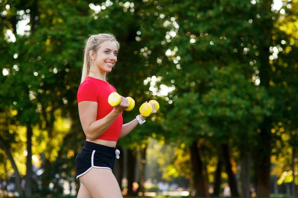 A young woman goes in for sports outdoors. girl with blond hair is training in the park on the nature — Stock Photo, Image