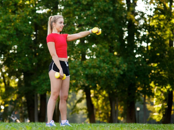 Una joven entra para practicar deportes al aire libre. chica con pelo rubio está entrenando en el parque en la naturaleza. —  Fotos de Stock