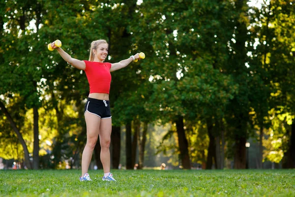 Una joven entra para practicar deportes al aire libre. chica con pelo rubio está entrenando en el parque en la naturaleza. —  Fotos de Stock