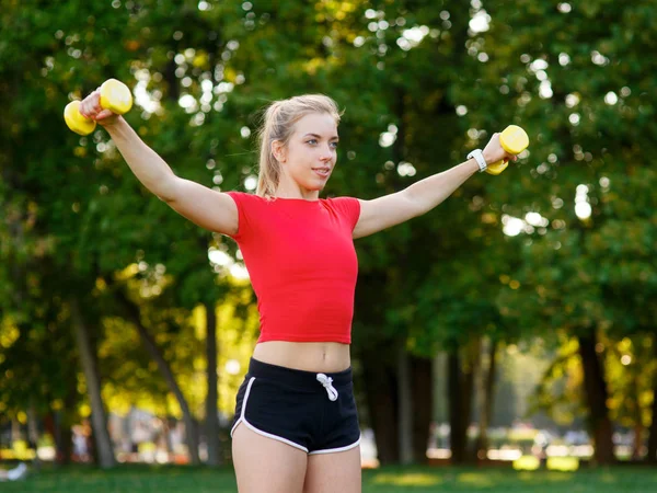 A young woman goes in for sports outdoors. girl with blond hair is training in the park on the nature — Stock Photo, Image