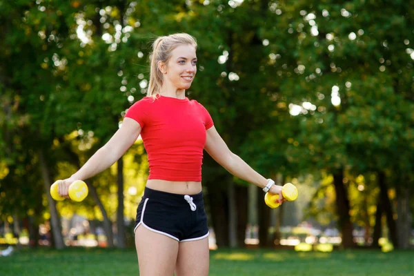 A young woman goes in for sports outdoors. girl with blond hair is training in the park on the nature — Stock Photo, Image