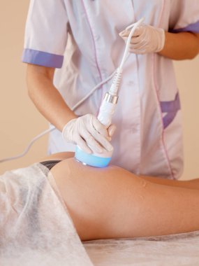 Donanım kozmetolojisi. Vücut bakımı. Spa tedavisi. Ultrason boşluğu, vücut hatları, tedavi. Kadın güzellik salonunda anti-selülit ve anti-yağ tedavisi görüyor..