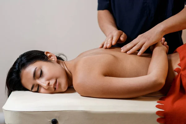 Mladá žena dostane masážní proceduru. Masér masíruje záda. — Stock fotografie