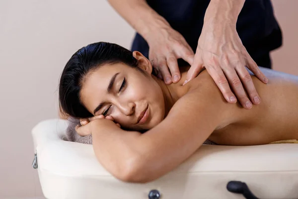 Een jonge vrouw krijgt een massage. Masseur maakt terug massage. — Stockfoto