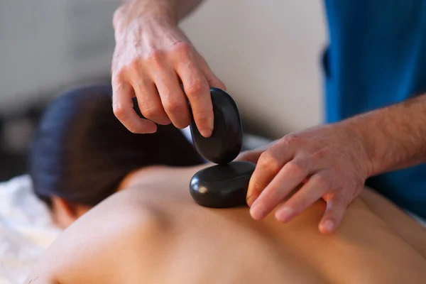 Mujer joven asiática que disfruta de los efectos terapéuticos de un masaje tradicional de piedra caliente en el lujoso spa y centro de bienestar. — Foto de Stock