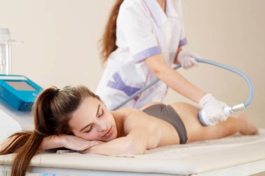 Donanım kozmetolojisi. Vücut bakımı. Spa tedavisi. Ultrason boşluğu, vücut hatları, tedavi. Kadın güzellik salonunda anti-selülit ve anti-yağ tedavisi görüyor..