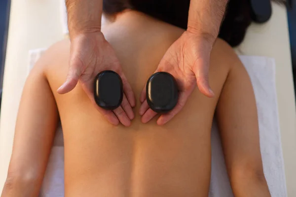 Junge Asiatin genießt die therapeutische Wirkung einer traditionellen Hot-Stone-Massage im luxuriösen Spa- und Wellnesszentrum — Stockfoto