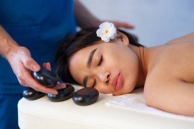 Spa'da sırtında taşlarla masaj masanın üzerinde yatan kadın