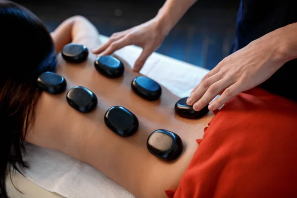 Young Asian woman enjoying the therapeutic effects of a traditional hot stone massage at luxury spa and wellness center — Stock Photo, Image