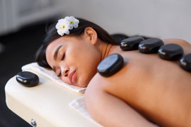 Spa'da sırtında taşlarla masaj masanın üzerinde yatan kadın