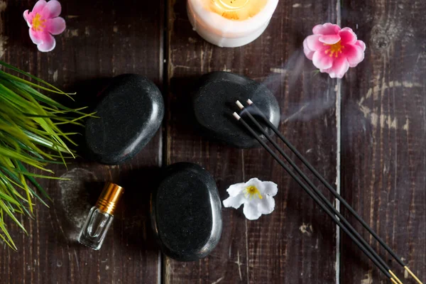 Piedras de masaje y vela de primer plano sobre un fondo oscuro de madera — Foto de Stock