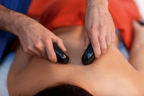 Mujer joven asiática que disfruta de los efectos terapéuticos de un masaje tradicional de piedra caliente en el lujoso spa y centro de bienestar. —  Fotos de Stock