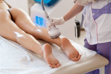 Donanım kozmetolojisi. Vücut bakımı. Spa tedavisi. Ultrason boşluğu, vücut hatları, tedavi. Kadın güzellik salonunda anti-selülit ve anti-yağ tedavisi görüyor..