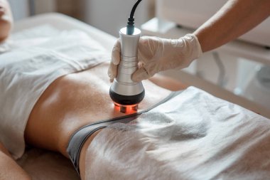 Donanım kozmetolojisi. Kapalı gözlü mutlu genç bir kadının bir güzellik salonunda rf kaldırma prosedürü uyguladığı resim..