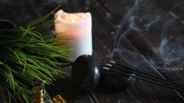 Masaj taşları ve mum, ahşap bir arka planda yakın plan. 