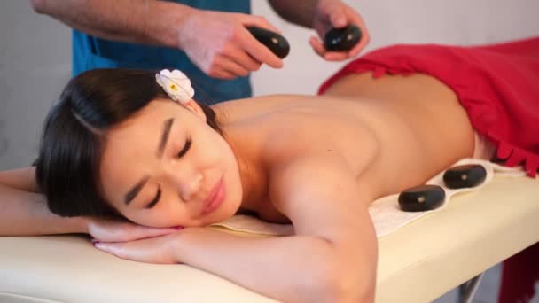 Male masseur does a back massage to a girl of Asian appearance. Relaxing and tonic massage. — Stockvideo