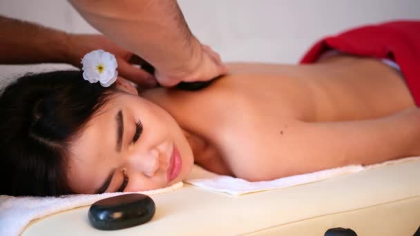 Mužský masér masíruje záda dívce asijského vzhledu. Relaxační a tonická masáž.