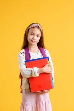 Kafkasyalı mutlu bir kızın kitaplı portresi. Uzun kızıl saçlı, güzel, pozitif kız kitabına sarılıyor, kameraya bak. Okula hazırlanıyor. izole edilmiş sarı arkaplan