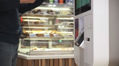 Genç bir adam telefon satın alır. Ulaşılmaz bir şekilde, self servis makinesinden. Erkekler telefonla öder. Kapat. 4k Video 