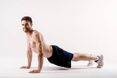 Beyaz arka plandaki bir adam sırtını esnetme egzersizi yapar. düz fileto yoga egzersizi.