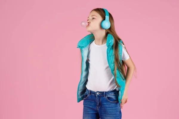 Una Niña Con Auriculares Explota Goma Mascar Rosa Sobre Fondo — Foto de Stock