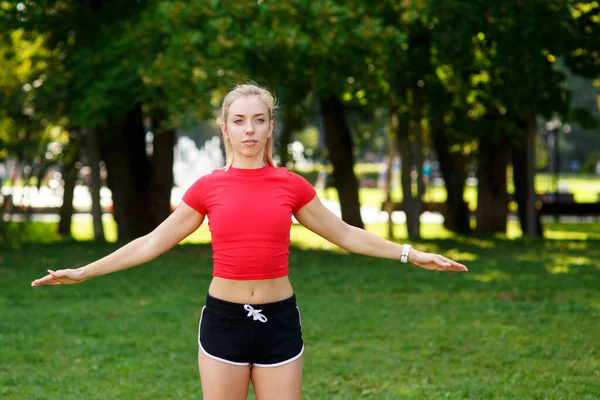 一个年轻的金发女孩在公园里做运动 一个女人在街上做热身运动 积极的户外运动 — 图库照片