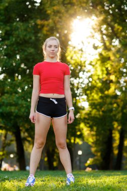 Bir bacağını dengede tutan beyaz bir kadın yoga savaşçısı, dışarıda, gün batımında sağlıklı bir kız, yaşam tarzı..