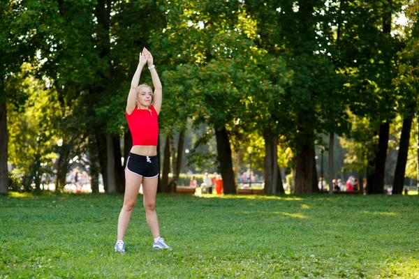 一个年轻的金发女孩在公园里做运动 一个女人在街上做热身运动 积极的户外运动 — 图库照片