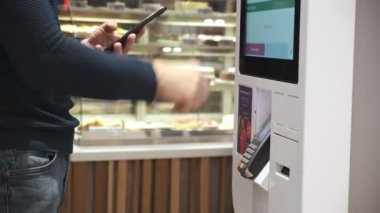 Genç bir adam telefon satın alır. Ulaşılmaz bir şekilde, self servis makinesinden. Erkekler telefonla öder. Kapat. 4k Video 