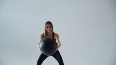 Spor salonundaki spor salonunda omuz presi antrenmanı için sağlık topu tutan formda bir kız. Genç Asyalı