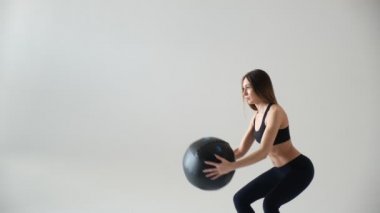 Spor salonundaki spor salonunda omuz presi antrenmanı için sağlık topu tutan formda bir kız. Genç Asyalı